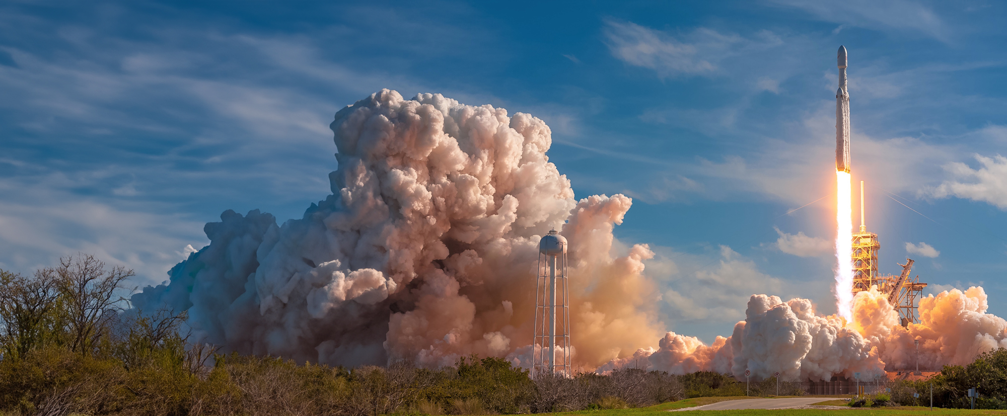 Rocket ship launching from pad with plume of smoke